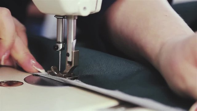Close-up of the hand of a seamstress at work. Sewing with a sewing machine The needle with a thread makes a stitch on the fabric. The suture sews the material with an electric sewing machine