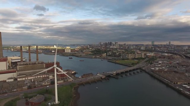 Aerial short shot of a spinning windmill with Boston downtown skyline in the background