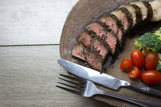 Crushed black pepper Lean meat slides Fresh vegetables on an old wooden cutting board