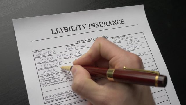 A person filling a liability insurance form. Closeup shot.