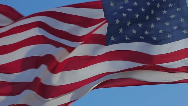 Close-up of an American flag flying in the wind against a background of clear sky. American Flag Waving. Close up of American flag waving. USA flag flaping in wind. American concept.