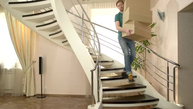 Man carrying stack of boxes. Young male walking downstairs. Common moving problems.