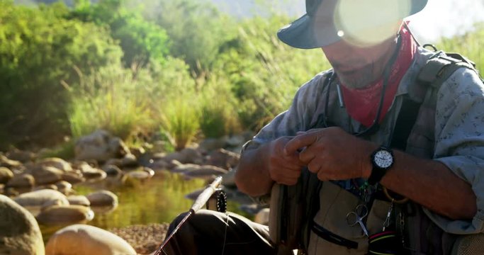Fly fisherman preparing string to tie on hook