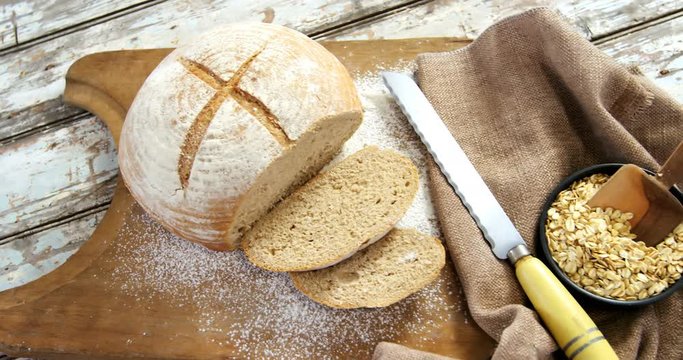 Bread loaf with knife and bowl of oats