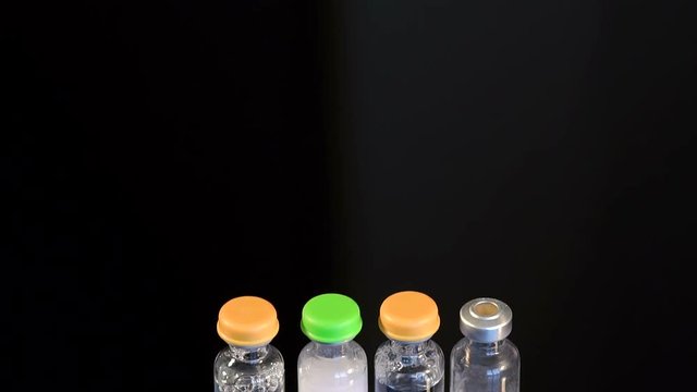 Four vials of insulin on a black background. Four ampoules for injection on a black background, close-up.