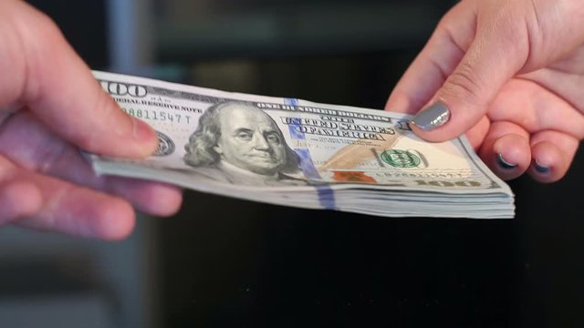 Close-up of a female's hand gives a lot of dollar bills to the man, slow motion.