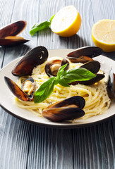 Pasta with mussels and lemons over blue wood background