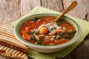Tomato soup with beans, spinach and parmesan close-up on the plate. Horizontal