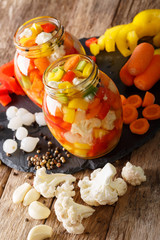 Obraz na płótnie Canvas Giardiniera salad from pickled cauliflower, pepper and carrots close-up in glass jars