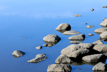 Stones in the river water under the sun rays