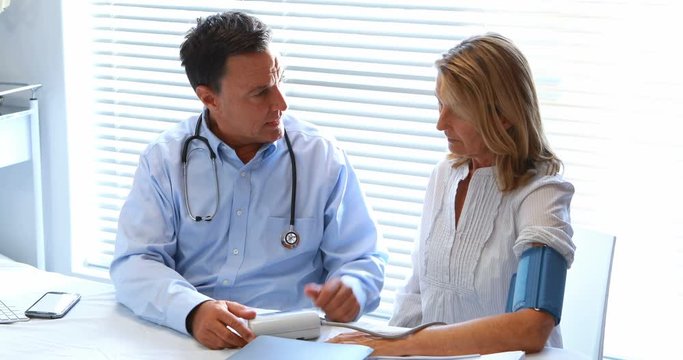 Doctor interacting with patient while checking blood pressure