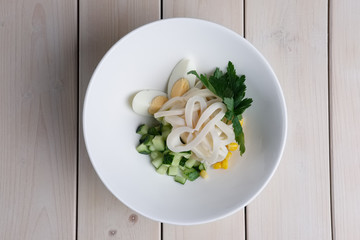Top view of salad with squid, corn, rice, egg and fresh cucumber