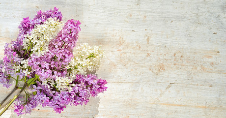 bouquet of white and violet lilac flowers on a wooden table with copy space