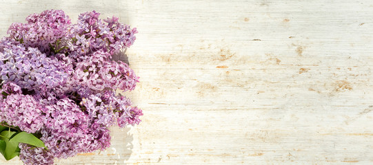 frame of lilac at the short side of the wooden background, top view with copy space