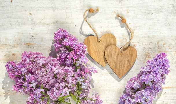 two wooden hearts with copy space for your text and bunch of lilac flowers on the wooden painted background