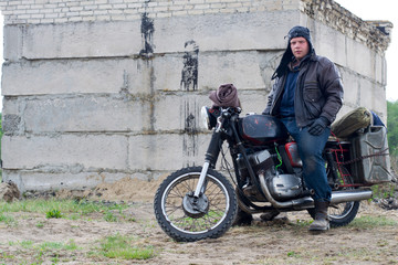 Obraz na płótnie Canvas A post apocalyptic man on motorcycle near the destroyed building