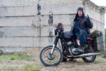 Fototapeta na wymiar A post apocalyptic man on motorcycle near the destroyed building