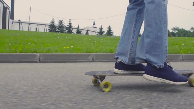 Foots of young man riding on longboard