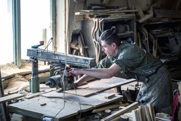 a man works on the machine with the wooden product