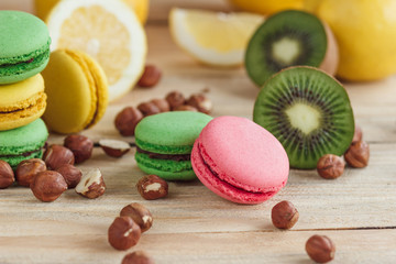 Green, pink, yellow and brown french macarons with lemon, kiwi and hazelnuts