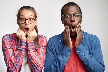 Two astonished fascinated young students in stylish wear staring at camera in full disbelief, keeping mouths opened, shouting in shock, surprised with greatly reduced prices of electronics. Wow, Omg