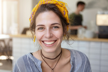 Excited woman with beutiful appearance wearing yellow scarf and stripped shirt sitting against home...