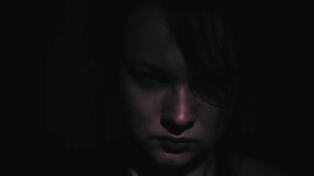 Serious face of a girl in the dark close-up