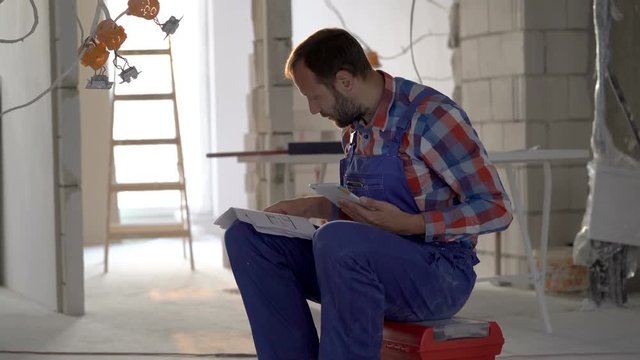 Worker checking projects and using tablet in his new flat, steadycam shot
