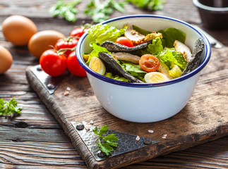 Beautiful Caesar salad with black croutons on a wooden board.