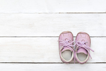 Pink little shoes on a white wooden background