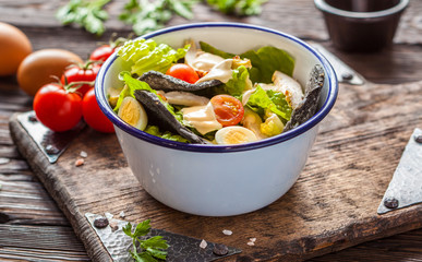 Beautiful Caesar salad with black croutons on a wooden board.