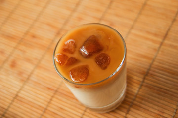 A glass of milk with coffee ice on the brown wooden background.