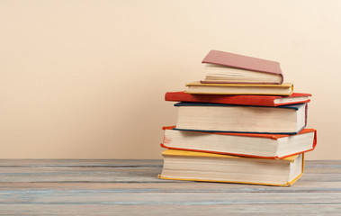 Book stacking. Open hardback books on wooden table and beige background. Back to school. Copy space for ad text