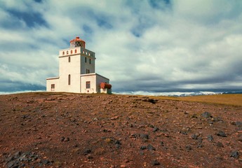 Leuchtturm auf steiniger Küste in Island
