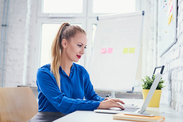 Attractive woman working on laptop in start-up office