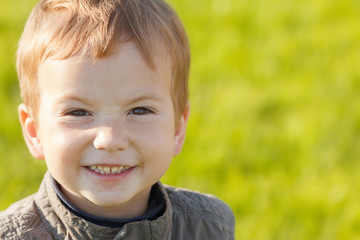 Portrait redhead child boy smiling on background of green grass