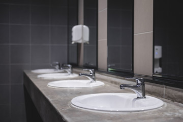 Fototapeta na wymiar Faucets with washbasin in public restroom