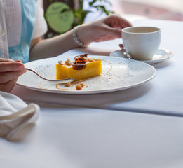 Woman at a restaurant eating a mango cake with tea. Restaurant food concept.