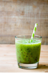 Healthy green smoothie in a glass on old wood.