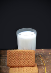biscuit and milk on wooden black background
