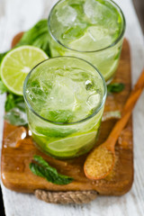 Mojito and ingredients on white wooden surface