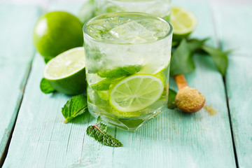 Mojito and ingredients on turquoise wooden surface