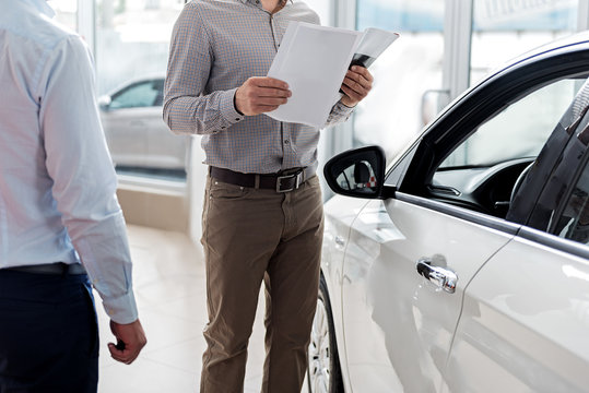 Visitor looking through agreement in car dealership