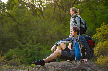 Man and woman traveler outdoors. Hikers couple takes a rest during hiking. Travel, vacation, holidays and adventure concept.