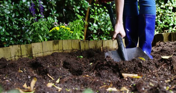 Person mixing soil with shovel in garden