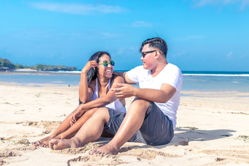 Asian couple sitting on the beach of tropical Bali island, Indonesia.