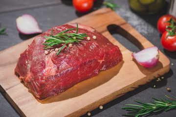 Raw beef on a cutting board  with spices and ingredients for cooking.