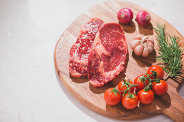 Raw beef on a cutting board  with spices and ingredients for cooking.