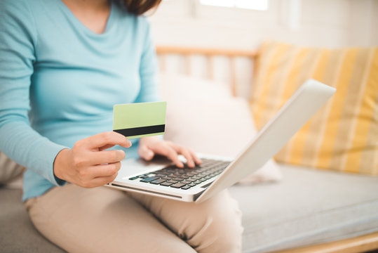 Online shopping concept. Young asian woman holding credit card and using laptop computer.