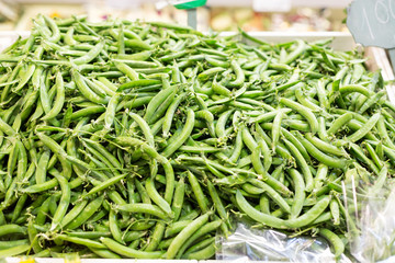 Green pea pods at market as a background. Selective focus